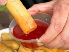 a person dipping some food into a small cup with ketchup on the side