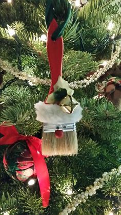 an ornament hanging from a christmas tree decorated with red and green ribbons, bells and ornaments