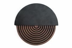 a black and brown circular object on a white wall with circles in the center,