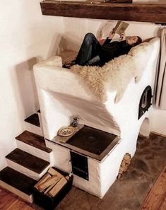 a woman laying on top of a stove in a room with wooden floors and stairs