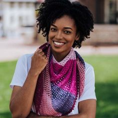 a smiling woman wearing a colorful scarf in the grass with her hands on her hips