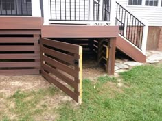 a wooden deck with stairs leading up to the top floor and below it is an open door