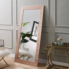 a large mirror sitting on top of a wooden floor next to a chair and table