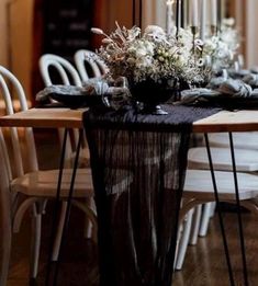 the table is set with white chairs and black linens for an elegant dinner party