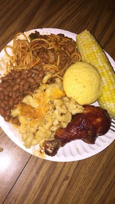 a white plate topped with different types of food on top of a wooden table next to a fork