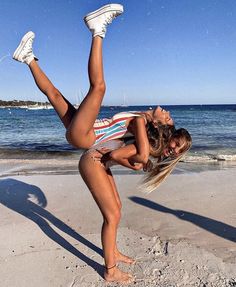 a woman is doing a handstand on the beach with her feet in the air