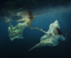 two women in white dresses floating under water