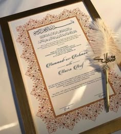 a wedding program with a feather quill and pen on it's side, sitting on a table