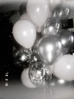 a bunch of balloons that are in the air with some silver and white balls on them