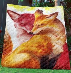 a quilt with two foxes on it in the grass