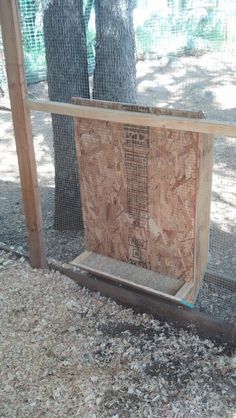 a chicken coop with the door open and wood paneling on the floor next to it