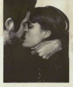 a man and woman kissing each other with tattoos on their arms