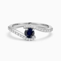 a white gold ring with a blue sapphire and diamonds on the band, set in 18k white gold