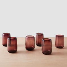 five brown glass cups sitting on top of a wooden table