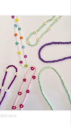 beaded necklaces and bracelets laid out on a white surface with beads in the shape of flowers