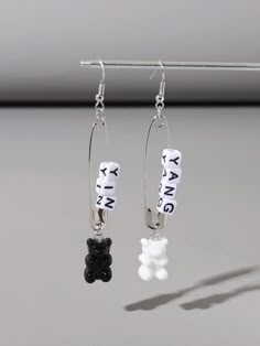 two black and white beads are hanging from silver earwires with words on them