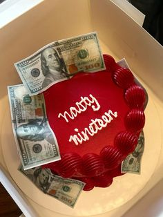 a red cake sitting on top of a white box covered in money and the words happy new year written on it