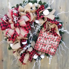 a red and black christmas wreath on a wooden wall with merry christmas y'all sign