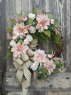 a wreath with pink flowers and greenery on a bench