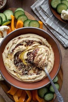 hummus and cucumbers in a bowl with a spoon