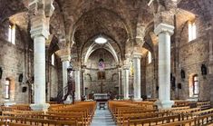 the inside of an old church with wooden pews and stone arches on both sides