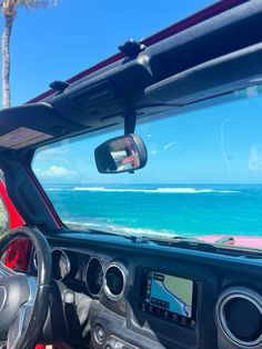 the dashboard of a car with an ocean view in the background and palm trees to the side