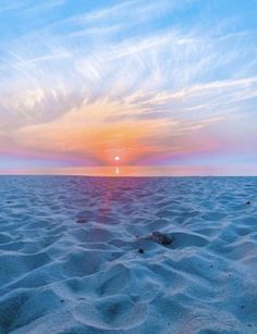 the sun is setting over an empty beach