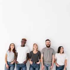 four people standing in front of a white wall with their hands on their hipss