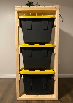 three black plastic storage bins sitting on top of a wooden shelf