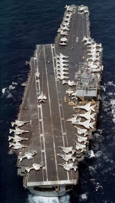 an aircraft carrier in the middle of the ocean with planes on it's deck