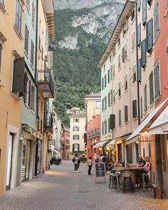 people are sitting at tables in the middle of an alleyway with mountains in the background