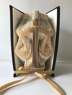 an origami book folding into a bow with ribbon on the front and back