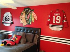 a bedroom decorated in red and black with hockey jerseys on the wall