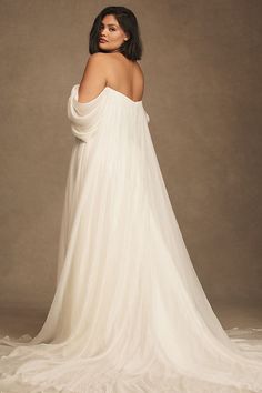 a woman in a white wedding dress with her back to the camera, posing for a photo