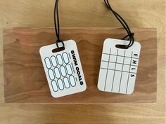 two tags with numbers are hanging on a wooden board that has string attached to it