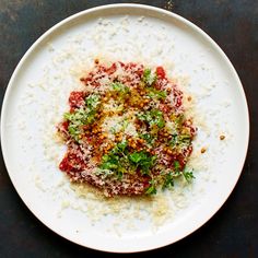 a white plate topped with rice covered in sauce and parmesan sprinkles