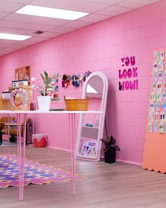 a room with pink walls and lots of decorations on the wall, including a desk