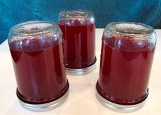 three jars filled with red liquid sitting on top of a white table next to each other