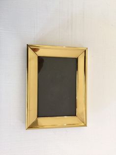 a gold frame hanging on the wall with a black board in it's center