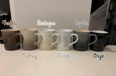 five coffee mugs are lined up on a counter top with the names of different colors