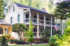 a large white house sitting in the middle of a lush green forest filled with trees