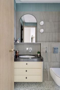 a bathroom with a sink, mirror and bathtub next to a wall mounted toilet