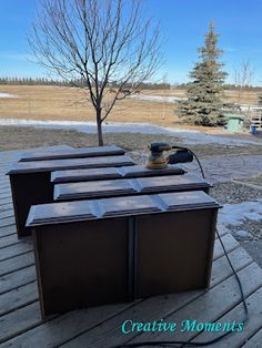 there are many bins on the deck outside in the snow and some bare trees