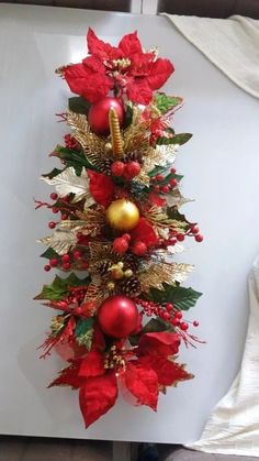 a christmas tree with red and gold ornaments on it's sides, hanging from a wall