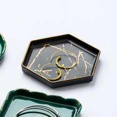 three green plates with gold designs on them and one has a ring in the middle