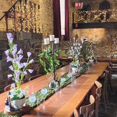 a long table with flowers and candles on it in front of a stone wall at a restaurant