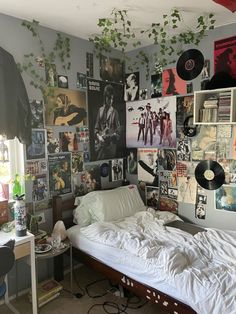 an unmade bed sitting in a bedroom next to a wall with pictures on it