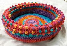 a colorful crocheted basket sitting on top of a bed