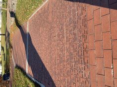 a brick wall with writing on it next to a street sign and grass in the background