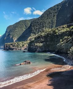 the beach is surrounded by mountains and water